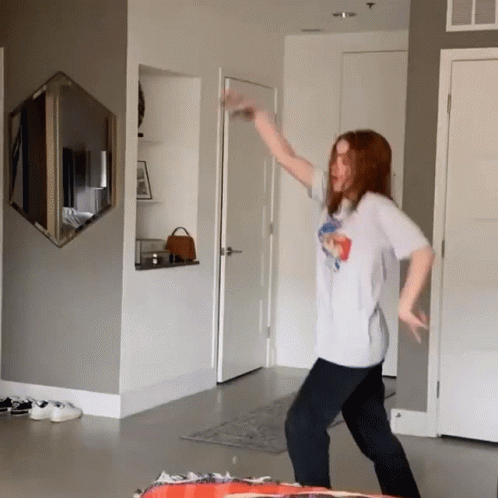 A Woman Is Dancing In A Room With A Mirror On The Wall GIF
