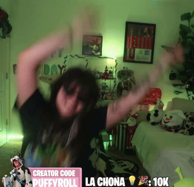 A Woman Is Dancing In A Room With A Sign That Says Creator Code Puffyroll La Chona 10K GIF
