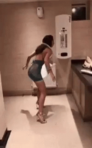 A Woman Is Dancing In A Room With A White Wall . GIF