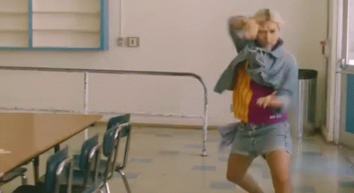 A Woman Is Dancing In A Room With Chairs And A Table . GIF