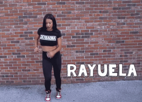 A Woman Is Dancing In Front Of A Brick Wall And The Name Rayuela Is On The Ground GIF