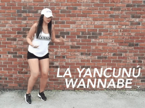 A Woman Is Dancing In Front Of A Brick Wall That Says La Yancunun Wannabe GIF
