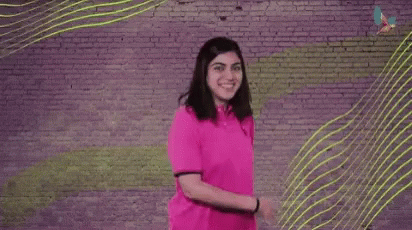 a woman is dancing in front of a brick wall with the words `` we got this '' written on it .