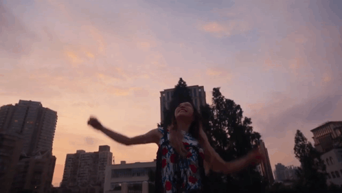 A Woman Is Dancing In Front Of A City Skyline GIF