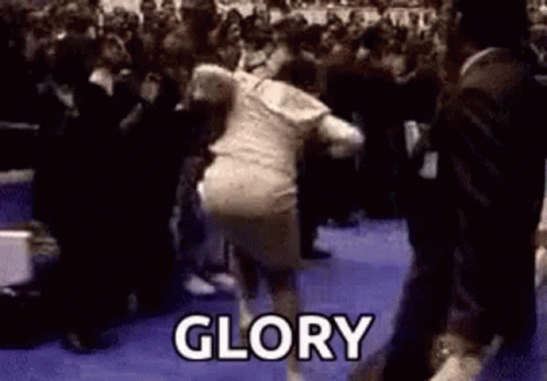 A Woman Is Dancing In Front Of A Crowd And The Word Glory Is Written On The Floor . GIF