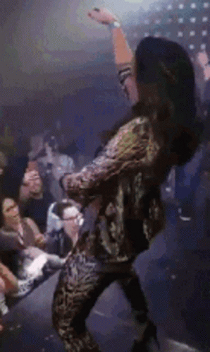 A Woman Is Dancing In Front Of A Crowd Of People At A Party . GIF