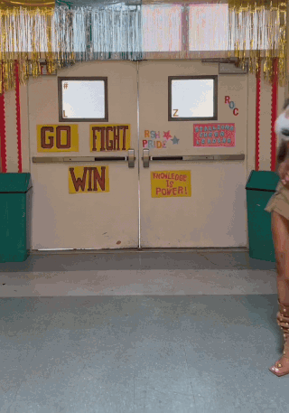 a woman is dancing in front of a door that says go fight win on it