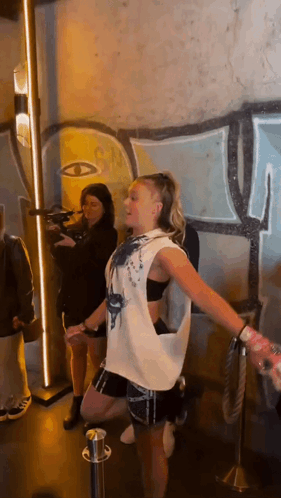 A Woman Is Dancing In Front Of A Graffiti Wall . GIF