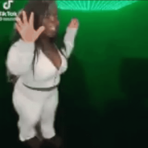 A Woman Is Dancing In Front Of A Green Background . GIF