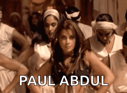 A Woman Is Dancing In Front Of A Group Of People And The Name Paul Abdul Is On The Bottom GIF