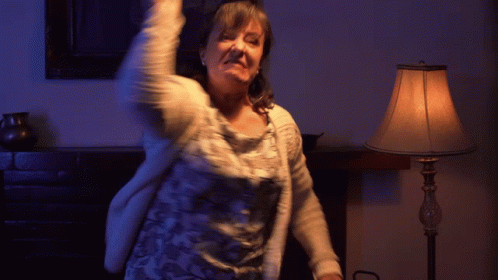 A Woman Is Dancing In Front Of A Lamp In A Room GIF