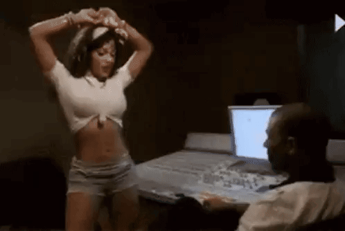 A Woman Is Dancing In Front Of A Man Sitting At A Desk . GIF