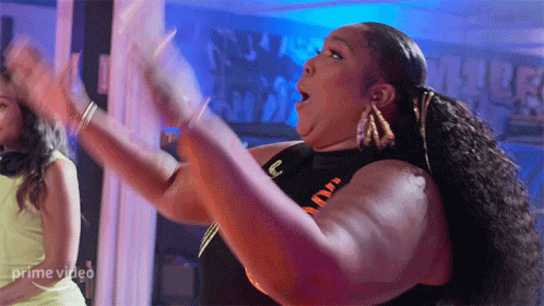 A Woman Is Dancing In Front Of A Sign That Says Prime Video On It GIF