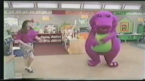 A Woman Is Dancing Next To A Purple Dinosaur In A Classroom . GIF