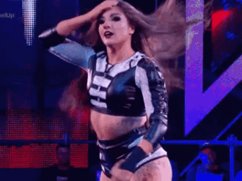 A Woman Is Dancing On A Stage In A Wrestling Ring . GIF