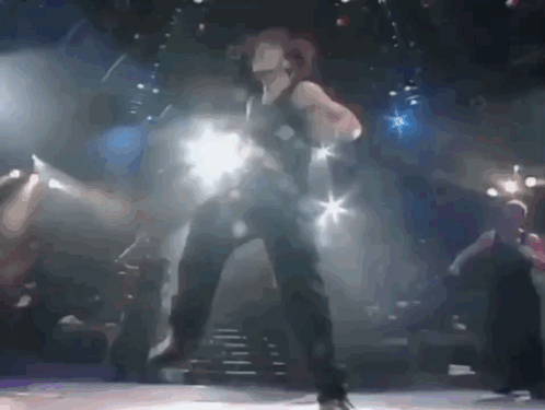 A Woman Is Dancing On A Stage With A Blurred Background GIF