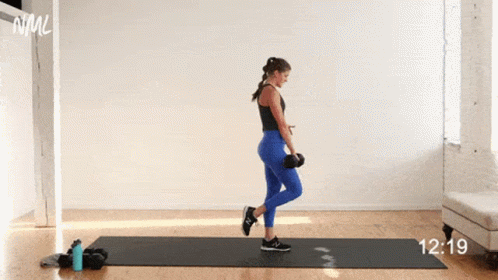 A Woman Is Doing A Balance Exercise With A Dumbbell On A Yoga Mat . GIF
