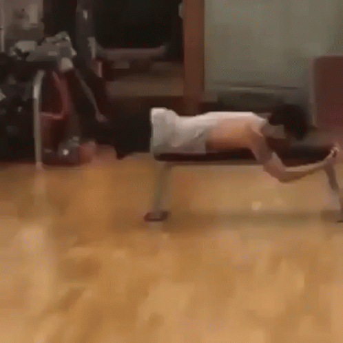 A Woman Is Doing Push Ups On A Bench In A Room . GIF