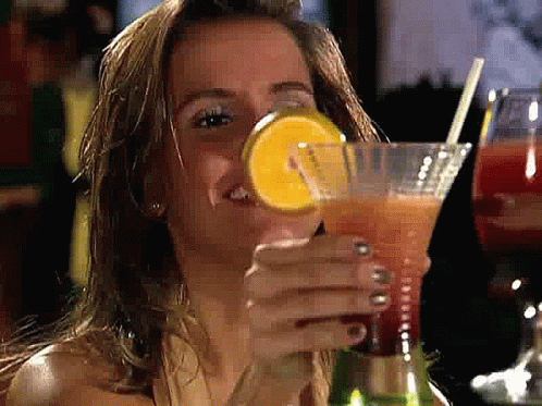 A Woman Is Drinking A Cocktail With A Straw And A Slice Of Lemon GIF