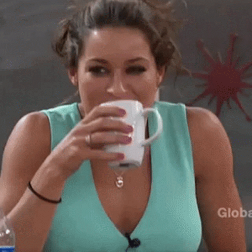 A Woman Is Drinking A Cup Of Coffee With A Globe Logo In The Background GIF