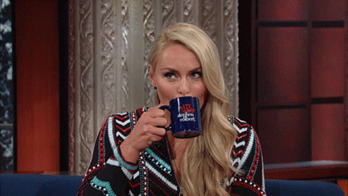 a woman is drinking from a blue mug that says the tonight show with jimmy fallon