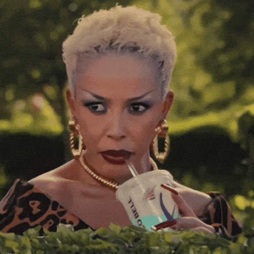 A Woman Is Drinking From A Cup That Says O Bell GIF