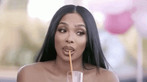A Woman Is Drinking From A Glass With A Straw . GIF
