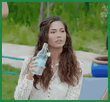 A Woman Is Drinking Water From A Bottle While Sitting On A Bench . GIF