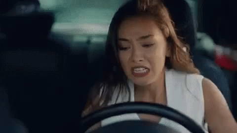 A Woman Is Driving A Car And Making A Face . GIF