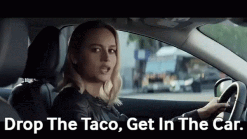 A Woman Is Driving A Car And Saying `` Drop The Taco , Get In The Car '' . GIF