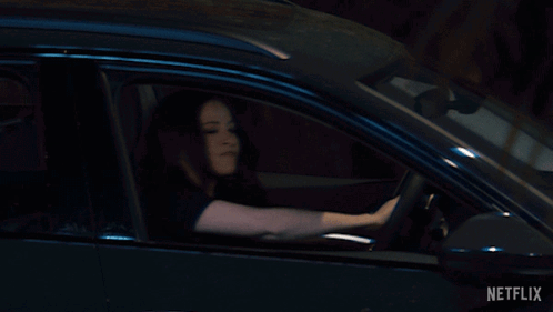 A Woman Is Driving A Car With Netflix Written On The Bottom Right GIF