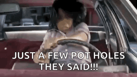 A Woman Is Driving A Car With The Words `` Just A Few Pot Holes They Said '' Written On The Screen . GIF