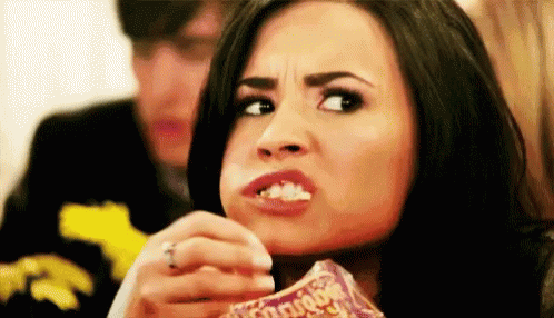 A Woman Is Eating A Bag Of Chips And Making A Face . GIF