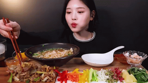 a woman is eating a bowl of noodles with chopsticks