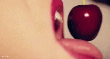A Woman Is Eating A Cherry With Her Tongue . GIF