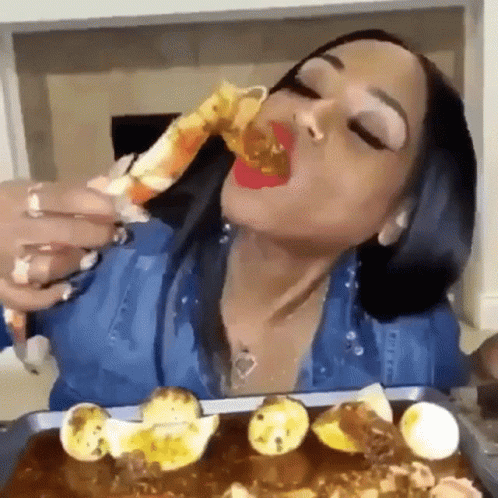 A Woman Is Eating A Crab Leg With A Spoon . GIF