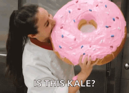 A Woman Is Eating A Giant Pink Donut With The Words Is This Kale GIF