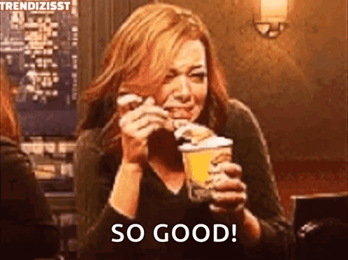 A Woman Is Eating A Hamburger And Holding A Cup Of Ice Cream And Saying So Good . GIF