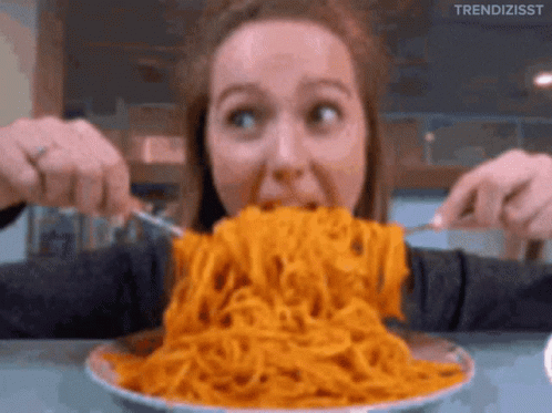 A Woman Is Eating A Large Bowl Of Spaghetti With A Fork And Knife GIF