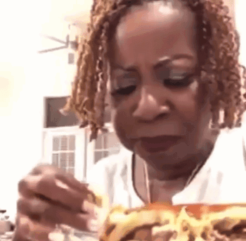 A Woman Is Eating A Sandwich With A Fork And A Spoon . GIF