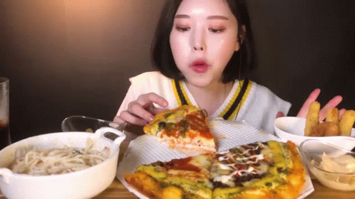 A Woman Is Eating A Slice Of Pizza And French Fries . GIF