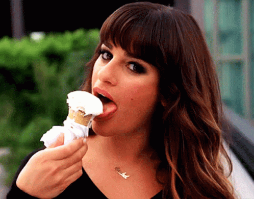 A Woman Is Eating An Ice Cream Cone With Her Tongue Hanging Out GIF