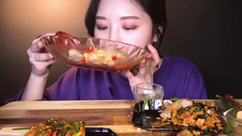 A Woman Is Eating Food From A Glass Bowl GIF