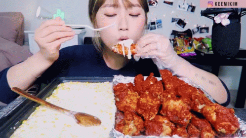 A Woman Is Eating Fried Chicken With A Fork And The Word Keemikim Is On The Bottom Right GIF