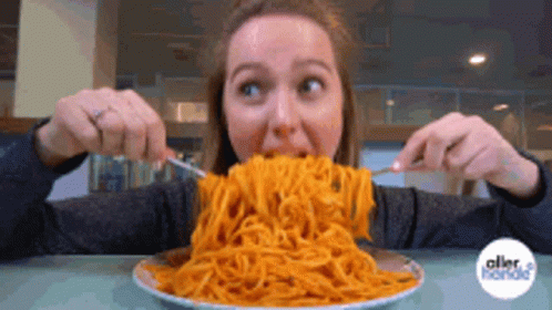 A Woman Is Eating Spaghetti With A Fork And Knife GIF