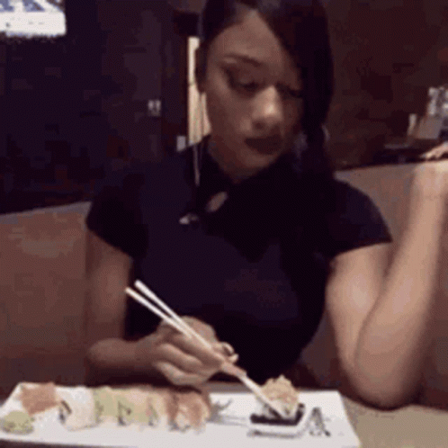 A Woman Is Eating Sushi With Chopsticks . GIF