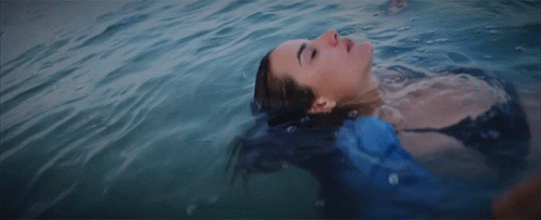 A Woman Is Floating On Her Back In The Water GIF
