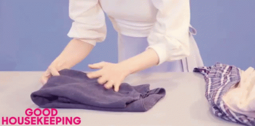 A Woman Is Folding Clothes And The Words Good Housekeeping Are Above Her GIF