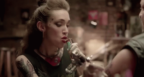 A Woman Is Getting A Tattoo On Her Arm In A Tattoo Parlor . GIF