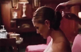 A Woman Is Getting Her Hair Done By A Man While Sitting On A Couch . GIF